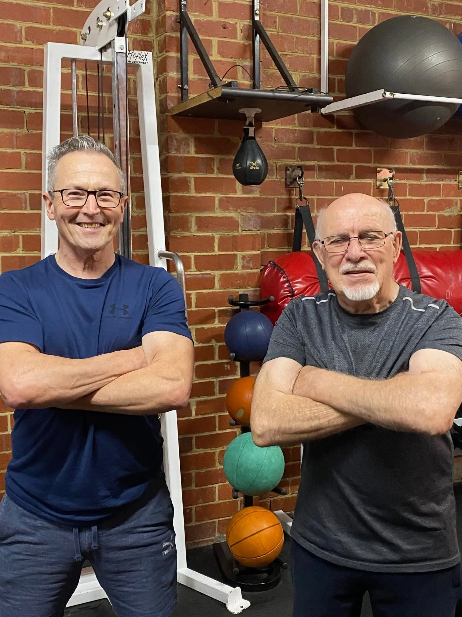 Dr Mark Navin with a senior patient in the clinic's rehabilitation gym — medicine balls and cable machine in the background